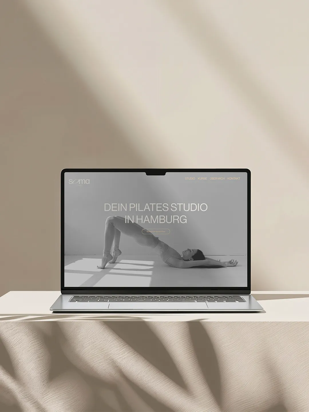 Laptop mit geöffneter Webseite eines Pilates-Studios in Hamburg, einer Frau im Pilates-Bridge-Übung auf dem Bildschirm.